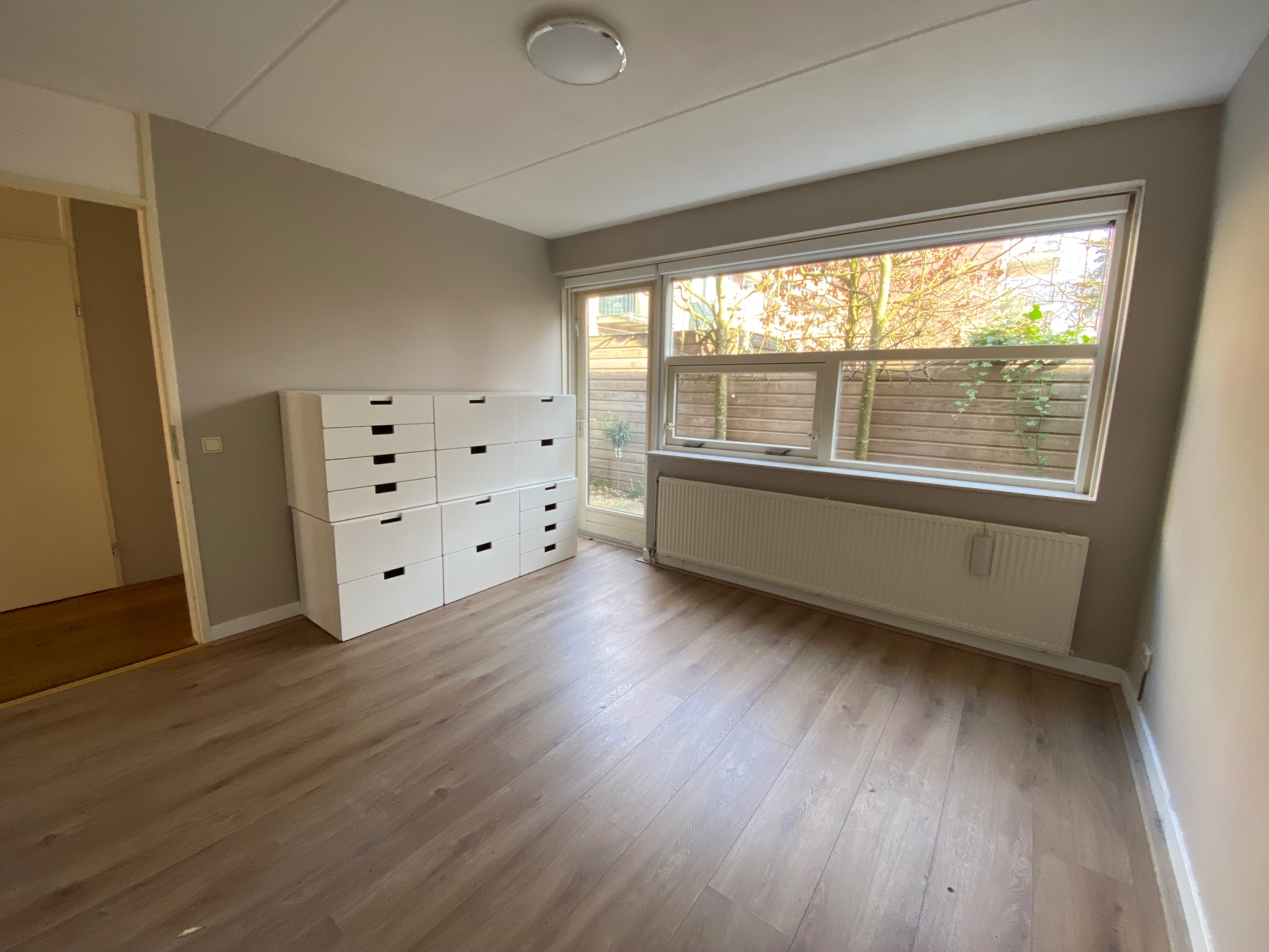 Slaapkamer met ladekast en uitzicht op de tuin